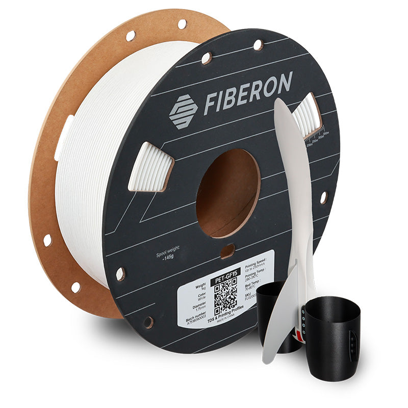 Spool of Fiberon 3D printing filament with a tool and black cup on a white background